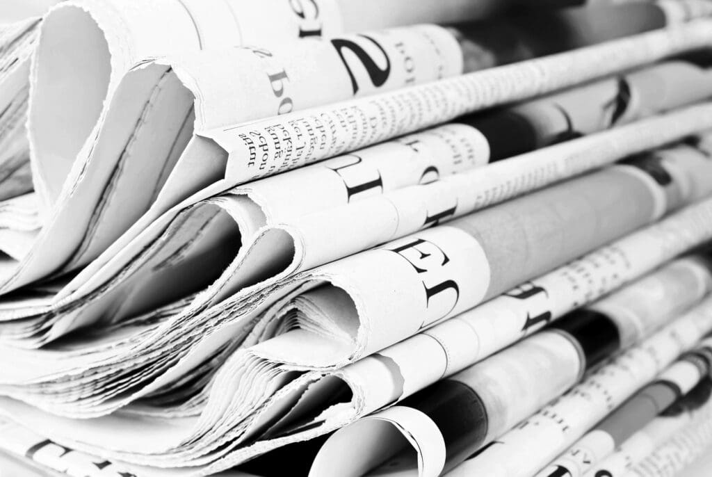 Stack of newspapers representing publishable legal news, publications and market developments
